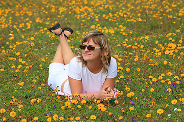 Image showing Young girl relaxing on a flowers meadow