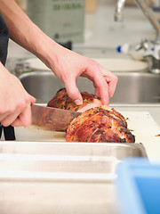 Image showing Chef cutting roast ham in a kitchen