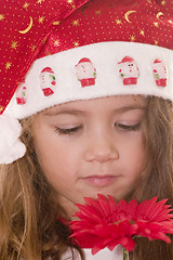 Image showing Little Santa smelling a flower