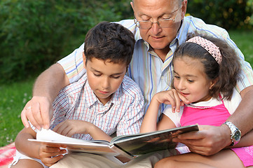 Image showing Grandfather and kids reading book