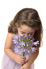 Image showing Young girl sniffing flower