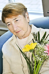 Image showing Sad elderly woman with flowers