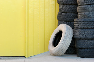 Image showing stack of tires against yellow wall