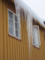 Image showing Icicle hanging from the roof of a yellow house