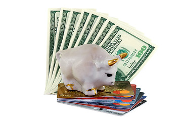 Image showing Figure of a white bull with gold horns standing on a pile of credit cards and dollars