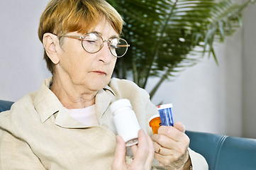 Image showing Elderly woman reading pill bottles