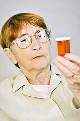 Image showing Elderly woman reading pill bottles