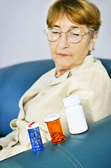 Image showing Elderly woman looking at pill bottles