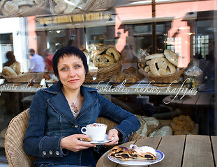 Image showing Young beautiful woman with a cup of hot cappuccino at a cafe