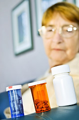 Image showing Elderly woman looking at pill bottles