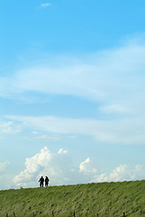 Image showing Two people male and female walking on a grass embankment against a big sky background
