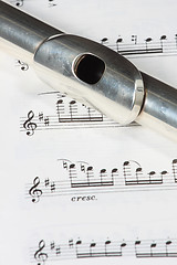 Image showing Silver flute instrument resting on a music score