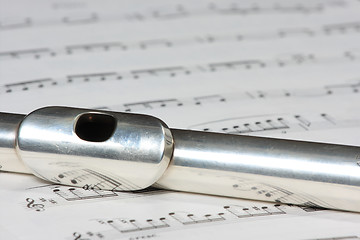 Image showing Silver flute instrument resting on a music score