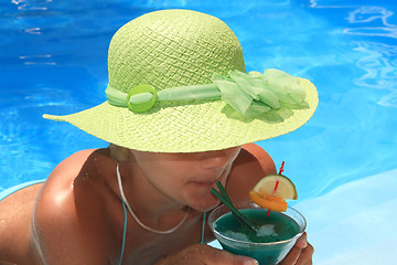 Image showing Woman enjoying a fresh cocktail in a blue pool