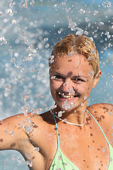 Image showing Young beautiful happy smiling tanned blond woman in bikini at rain or summer shower on sea beach