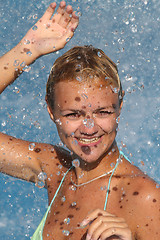 Image showing Young beautiful happy smiling tanned blond woman in bikini at rain or summer shower on sea beach