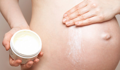 Image showing pregnant woman holding body lotion