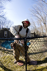Image showing   workman repairing building chain link fence