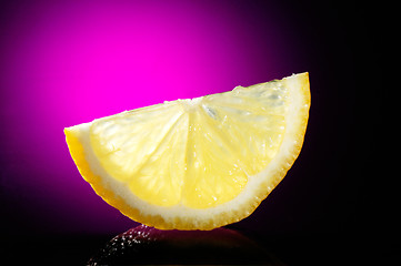 Image showing close-up of lemon slice on table glass and violet background