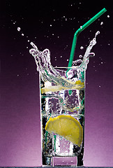 Image showing sliced lemon falling in glass of alcoholic drink with ice cubes 