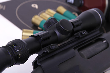 Image showing Shotgun with a rifle scope target and shotshell