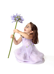 Image showing Little girl spinning a large stemmed flower with delight