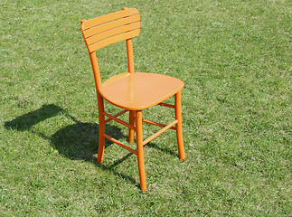 Image showing Orange wooden chair on grass