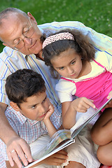 Image showing Grandfather and kids reading book 