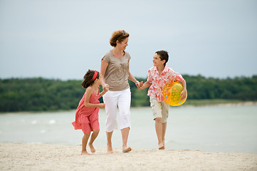 Image showing Mother and kids walking on the beach