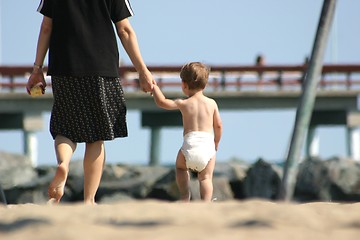 Image showing A toddler holds his mother's hand as he heads home from the beach.