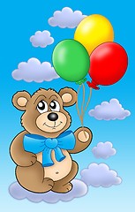 Image showing Teddy bear with color balloons on blue sky.