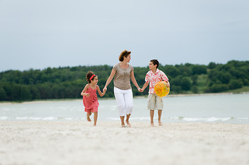 Image showing Mother and kids walking on the beach