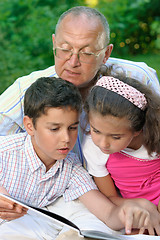 Image showing Grandfather and kids reading book