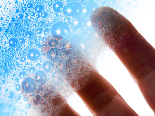 Image showing Fingers hold blue soap bubbles