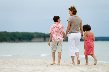 Image showing Mother and kids walking on the beach
