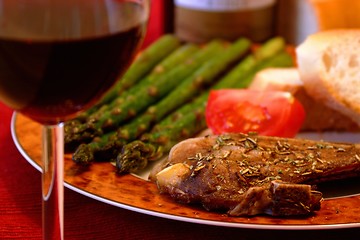 Image showing Meal of porkchops, asparagus, tomatoes and bread