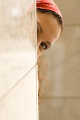 Image showing woman looking behind a wall