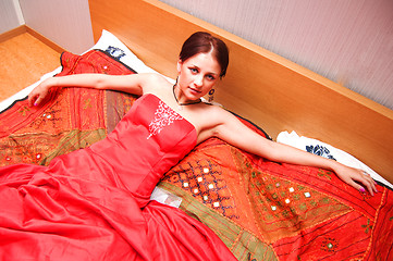 Image showing Beautiful woman in red dress lying on the bed