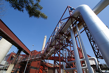 Image showing industrial pipelines on pipe-bridge against blue sky      