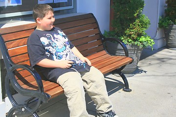 Image showing Young boy sitting on bench