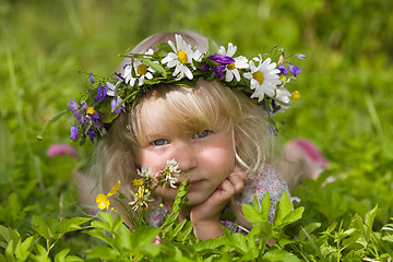 Image showing happy little girl in flowers wreath lying on green grass