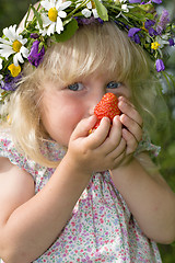 Image showing little girl in flowers wreat with strawberries in hands