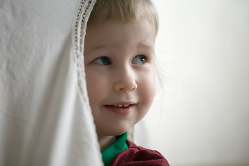 Image showing little girl behind window curtain