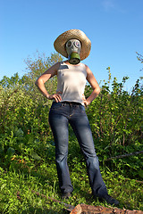 Image showing woman in gas-mask at garden work