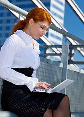 Image showing happy businesswoman with laptop in the city