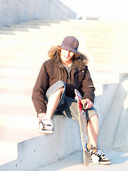 Image showing Modern teenager sitting with skateboard in hand