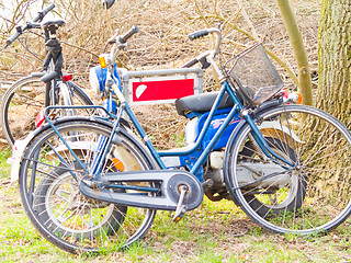 Image showing Old fashioned bikes resting against a sign