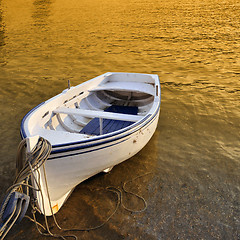 Image showing A small row boat beached on the shore at sunset - Cadaques, Spain