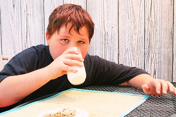 Image showing Young boy eating cookies and milk