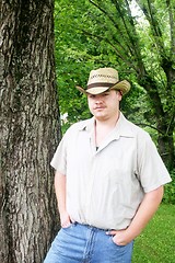 Image showing Young cowboy standing beside the tree